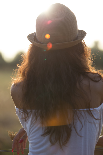 Country Girl: Young woman looking to the horizon with the sun making a lens flare.