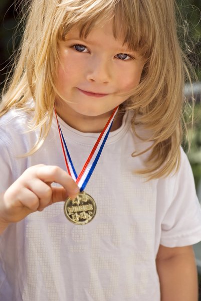 Child and medal: Little girl proudly showing her gold medal