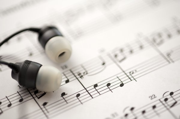 listening to music: a sheet of musical notes and some ear-bud headphones