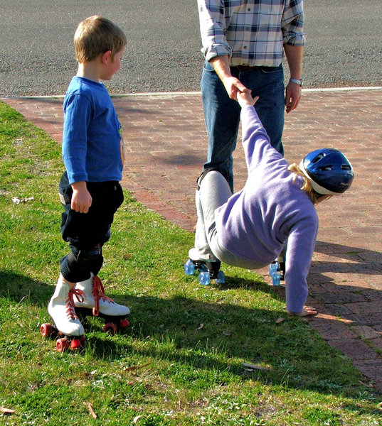 helping hand: fallen roller skater helped up by father