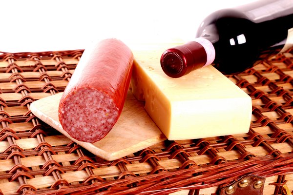 Wine, cheese and sausage on pi: A bottle of wine, some cheese and sausage on top on a picnic basket. Isolated with white background.