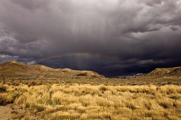 Storm over Mountains: Dark storm clouds with rainbow over western range.