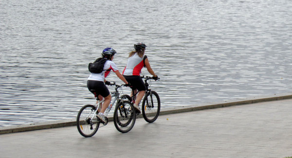 riverside cycling1: two women cyclists riding alongside the river