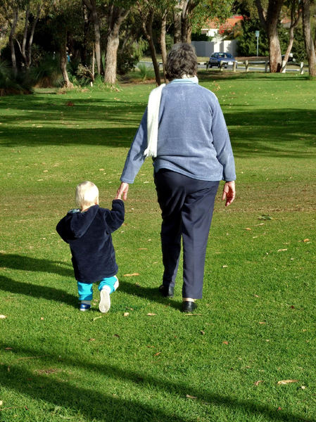 a walk with grandma1: grandmother taking toddler for walk in the park