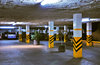 Parking lot: Shot of an underground parking lot in dim lights, cars in the background