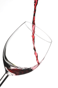 Glass of red wine: just start to poor in a glass with red finest wine