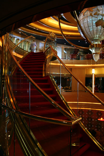 Grand Golden Staircase: Curved, red carpeted, gold handrail staircase.