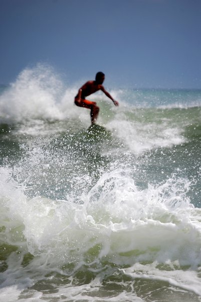 surf: Surfer, identity blurred, behind crashing surf at Kuta Beach