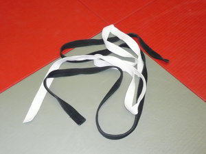 Judo: Judo belts on a tatami symbolizing the begin of a Judo career with the white belt and its masterchip with the black belt