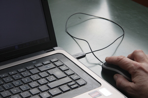 Using the mouse: Laptop and users hand moving a  mouse. Homeoffice
