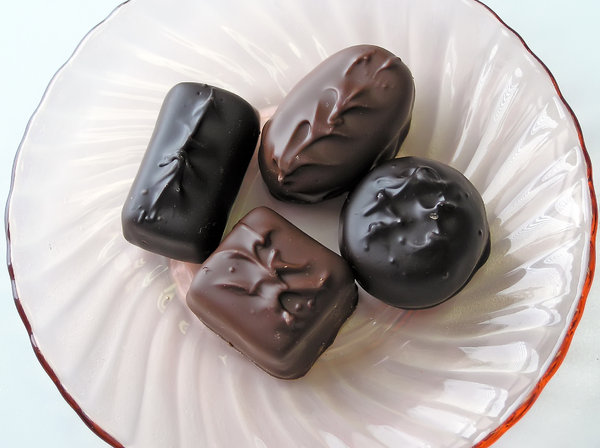 Chocolates on a Dish: Four chocolate candies on a clear pink glass plate.