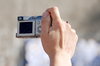 Compact photo camera in action: Woman's hand with little camera