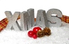 Xmas ribbon and  snow: Silver letters spelling XMAS in decoration snow with ribbon, red apple, red berries and golden cones