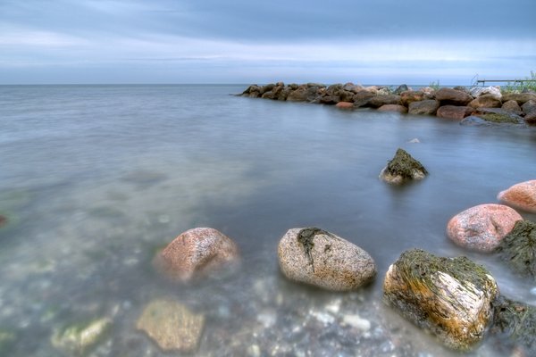 Smooth water - HDR: Coastline with peer, breakwater, seaweed and rocks in the water. The picture is HDR using seven images.