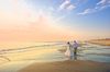 After the Sunrise Wedding: couple leaving the wedding ceremony, just after sunrise, on the beach