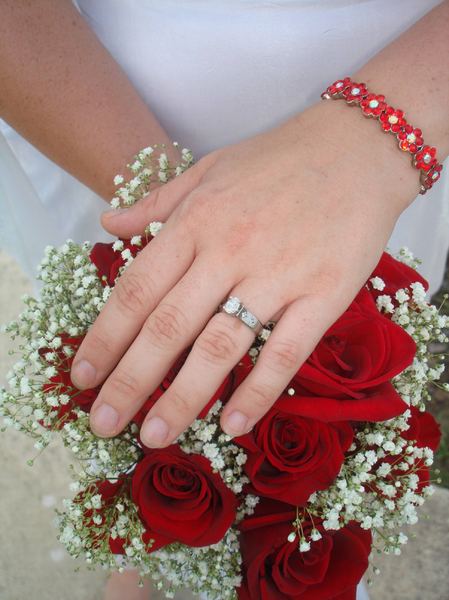 Wedding Ring and Flowers: Hand in front of flowers, instead of the normal holding the flowers, displaying the wedding ring