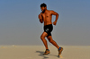 Young adult running the sun: Young adult man, is running on the sand hill in desert area and he is enjoying the sand and sunlight. His slim body suggests that he is a fitness model working out daily to maintain a healthy life style and healthy living habits. Fitness exercise and card