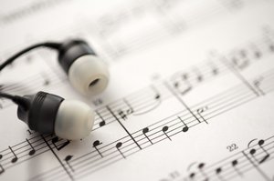 listening to music: a sheet of musical notes and some ear-bud headphones