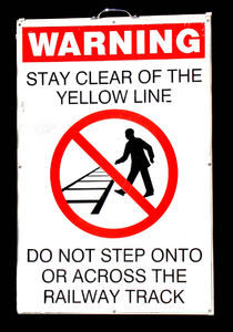 stand back: railway station warning sign near railway track