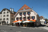 Sunny Serenity in La Brévine: A bright sunny day in the village square of La Brévine, often called the “Siberia of Switzerland.” The scene captures traditional Swiss architecture, clear blue skies, and a peaceful alpine atmosphere bathed in warm natural light.