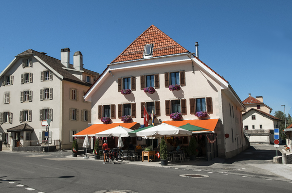 Sunny Serenity in La Brévine: A bright sunny day in the village square of La Brévine, often called the “Siberia of Switzerland.” The scene captures traditional Swiss architecture, clear blue skies, and a peaceful alpine atmosphere bathed in warm natural light.