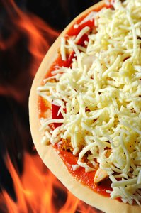 Pizza Prepared: A pizza topped with cheese on a flamed background ready to be cooked